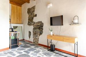 a room with a stone wall with a desk and a tv at Casa Sarvaega in Cogorno