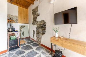 a room with a stone wall with a tv on the wall at Casa Sarvaega in Cogorno