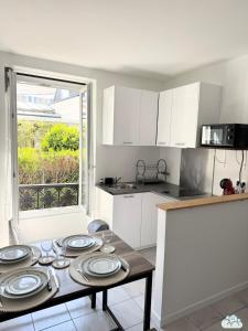 a kitchen with a table with plates on it at Au Fil de la Marne à 15mn Disney et 25mn Paris in Lagny