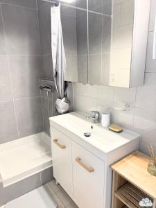 a white bathroom with a sink and a tub at Au Fil de la Marne à 15mn Disney et 25mn Paris in Lagny