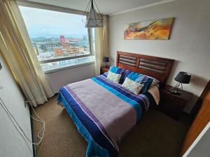 a bedroom with a bed and a large window at Departamentos Concepcion Centro in Concepción