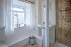 un bagno bianco con doccia e lavandino di Bullcroft - 6 Bedroom House - Oxwich a Swansea Altre 52 foto