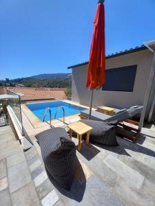 a patio with a red umbrella and chairs and a pool at Stavros luxury apartment in Skiathos Town