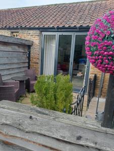 a porch of a house with a bunch of pink flowers at Larch Cottage Ruston with hot tub, dogs go free in Scarborough