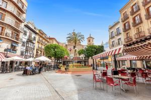 een stadsstraat met tafels en stoelen en een fontein bij Luxury and emblematic apartment in Murcia