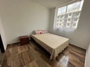 a small bedroom with a bed and a window at Casamora girardot in Estación El Salto