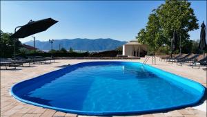 a large blue swimming pool with chairs and an umbrella at SM VIP HOUSES in Shanovo
