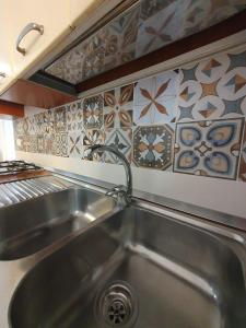 a stainless steel sink in a kitchen with tiles at House le Ancore in Barcellona-Pozzo di Gotto