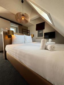 a bedroom with a large bed with white sheets and pillows at Hotel West Inn Aan Zee in Den Oever