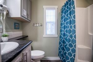 a bathroom with a blue shower curtain and a toilet at Riverfront Tiny House with Fire Pit in Seguin, Texas in Seguin +40 photos
