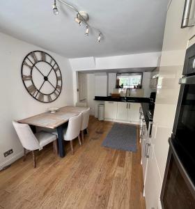 ein Esszimmer mit einem Tisch und einer Uhr an der Wand in der Unterkunft Bath Central Free Parking One Double Ensuite Room in Historical Mews Cottage in Bath