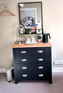 eine schwarze Kommode mit einem Spiegel darüber in der Unterkunft Bath Central Free Parking One Double Ensuite Room in Historical Mews Cottage in Bath