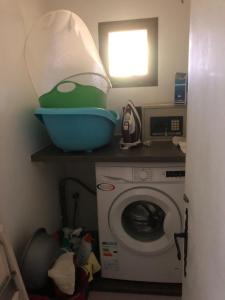 a laundry room with a washing machine and a bowl on a shelf at Rose cottage in Montcaret