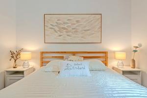 a bedroom with a white bed with two lamps at Les Terrasses de la Palud in Landéda