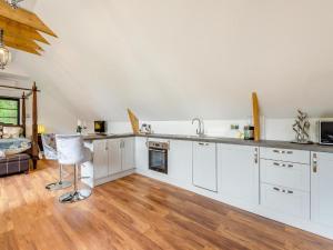 a kitchen with white cabinets and a wooden floor at Foxton Barn in Harrietsham
