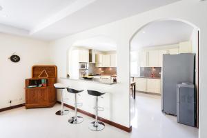 a white kitchen with a counter and stools in it at Baan Kaja Villa by Lofty in Surin Beach