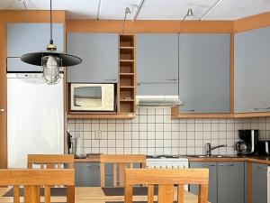 a kitchen with blue cabinets and wooden chairs at Holiday Home Karhunvartijan linna a1 by Interhome in Ruka