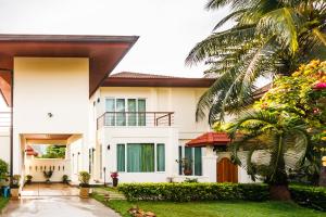 a white house with a palm tree in front of it at Baan Kaja Villa by Lofty in Surin Beach