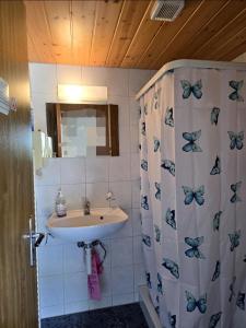 a bathroom with a sink and a shower curtain with butterflies at Doppelzimmer direkt vorm Emmental in Eriswil