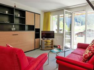 uma sala de estar com dois sofás vermelhos e uma televisão em Apartment Chalet Wyssefluh by Interhome em Grindelwald