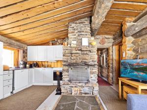 a kitchen with white cabinets and a stone wall at Holiday Home Kelokoto by Interhome in Saariselka