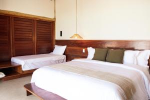a hotel room with two beds with white sheets at K08 Bangalôs in Galinhos