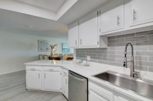 a kitchen with white cabinets and a stainless steel sink at El Matador 344 - Beautiful views of the Gulf and pool in Fort Walton Beach