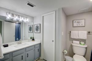 a bathroom with a sink and a toilet and a mirror at El Matador 344 - Beautiful views of the Gulf and pool in Fort Walton Beach