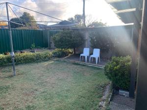 two white chairs and an umbrella in a yard at 76 Companion Crescent in Higgins