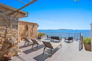 Eine Terrasse mit Stühlen und dem Meer im Hintergrund in der Unterkunft Maison sur l'eau-Hyères-Almanarre-Parkings Clim WIFI By HC in Hyères