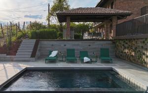 a swimming pool with green chairs and a gazebo at Casa Reis in San Damiano dʼAsti