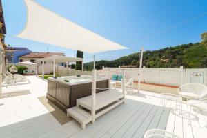 a hot tub on a deck with a white umbrella at Hotel Galli - Wellness & Spa in Fetovaia