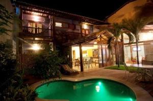a swimming pool in front of a house at night at Pousada Rosa dos Ventos in Praia do Forte
