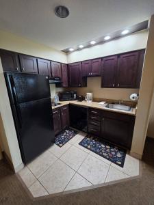 Una cocina con gabinetes de madera y un refrigerador negro. en 2 Queen Suite Near Disney SeaWorld, en Orlando
