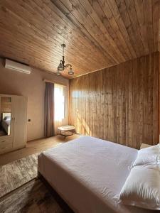 a bedroom with a large bed and a wooden wall at Villa Obcha - Whispering Vines Guesthouse in Bagdatʼi