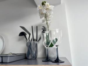 a table with two wine glasses and a vase with flowers at Comfy Apartment - 12 Mins from Gatwick in Ifield