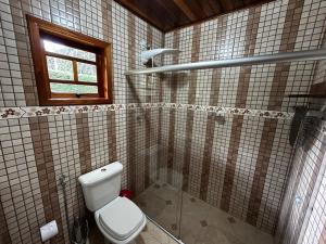 Un baño con inodoro y ventana. en Chale Sitio Esperança, en Sapucaí-Mirim 18 fotos más