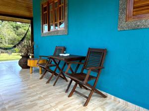 una mesa y sillas en una habitación con una pared azul en Chale Sitio Esperança, en Sapucaí-Mirim