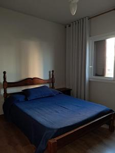a bedroom with a bed with blue sheets and a window at Comodidade ao lado da ESALQ USP in Piracicaba