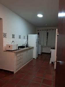 a kitchen with white appliances and a red tile floor at Comodidade ao lado da ESALQ USP in Piracicaba