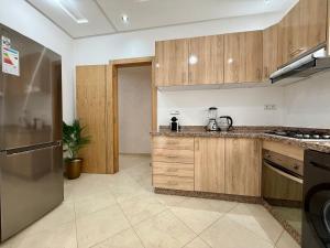 a kitchen with wooden cabinets and a refrigerator at Charming Bright Flat in Historic La Ville Haut in Kenitra +7 photos