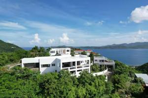 Little Carrot BaySolace Villa的水边山顶上的白色建筑
