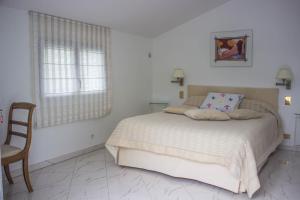 a white bedroom with a bed and a chair at Villa Yoda in Saint-Jean-de-Luz