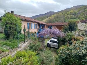 a house with a car parked in a garden at La Bergerie in Sost