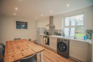 a kitchen with a wooden table and a table and a stove at Charming 3 Bedroom Home with Garden in Banbury in Banbury