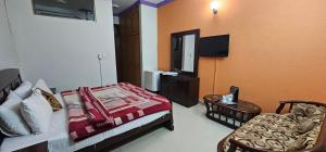 a bedroom with a bed and a chair and a television at The Host Lodge in Islamabad