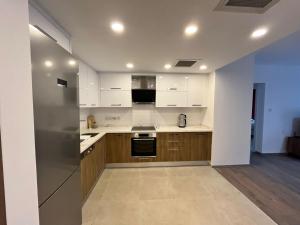 a kitchen with wooden cabinets and a stainless steel refrigerator at Olive Hill 14 Cozy 2-Bed Garden Apt by HolidayKeys in Kérynia
