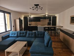 a living room with a blue couch and a kitchen at Le REFUGE DIEPPOIS plein centre ville BY HOLIDIEPPE in Dieppe
