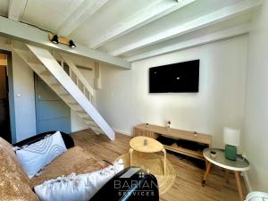 Una sala de estar con un sofá y un televisor en la pared. en Duplex confortable avec climatisation et cour - ménage et linge inclus, en La Rochelle