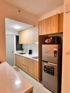 a kitchen with a stainless steel refrigerator and wooden cabinets at Gamuda Cove Homestay in Banting